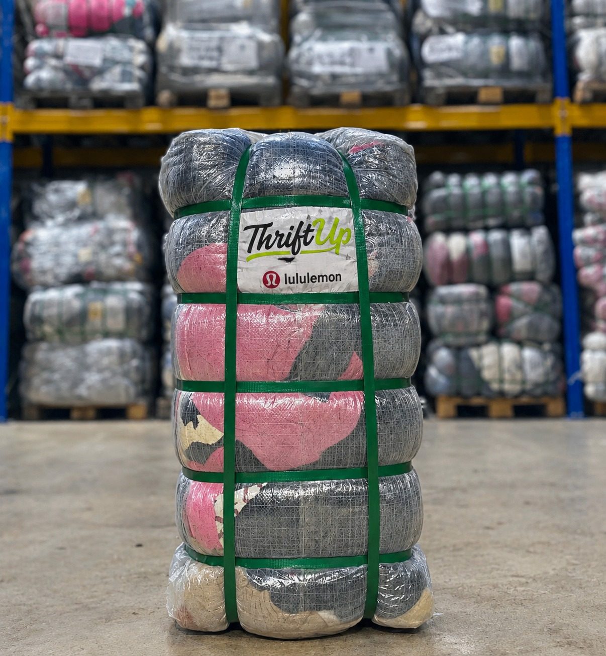 Strapped bale of pre-owned lululemon clothing with a ThriftUp label in a warehouse